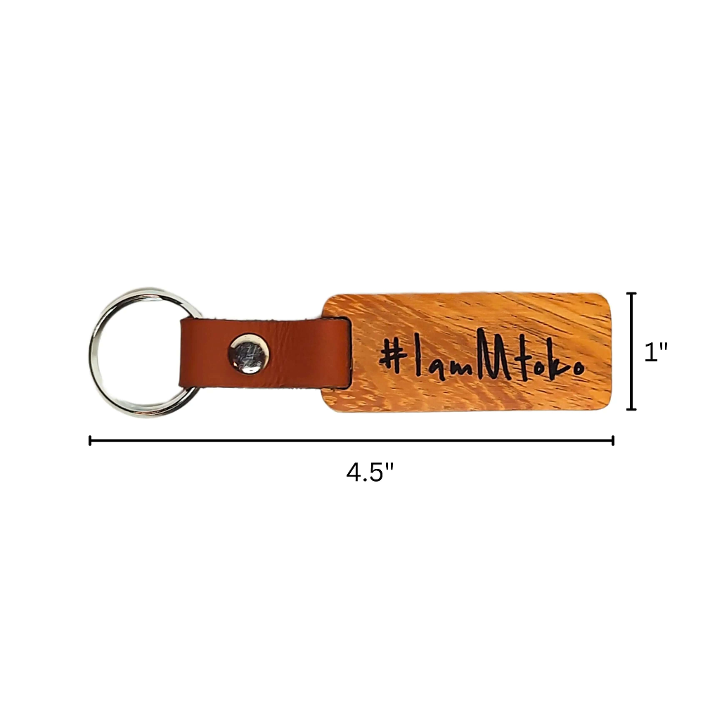 Handmade African keychain featuring wooden design and leather tag with #IamMtoko inscription.